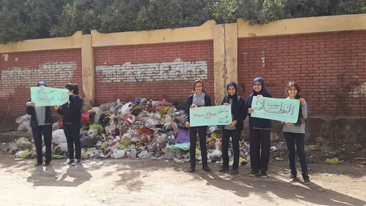 1-طلاب مدرسة يرفعون لافتات لرفع القمامة