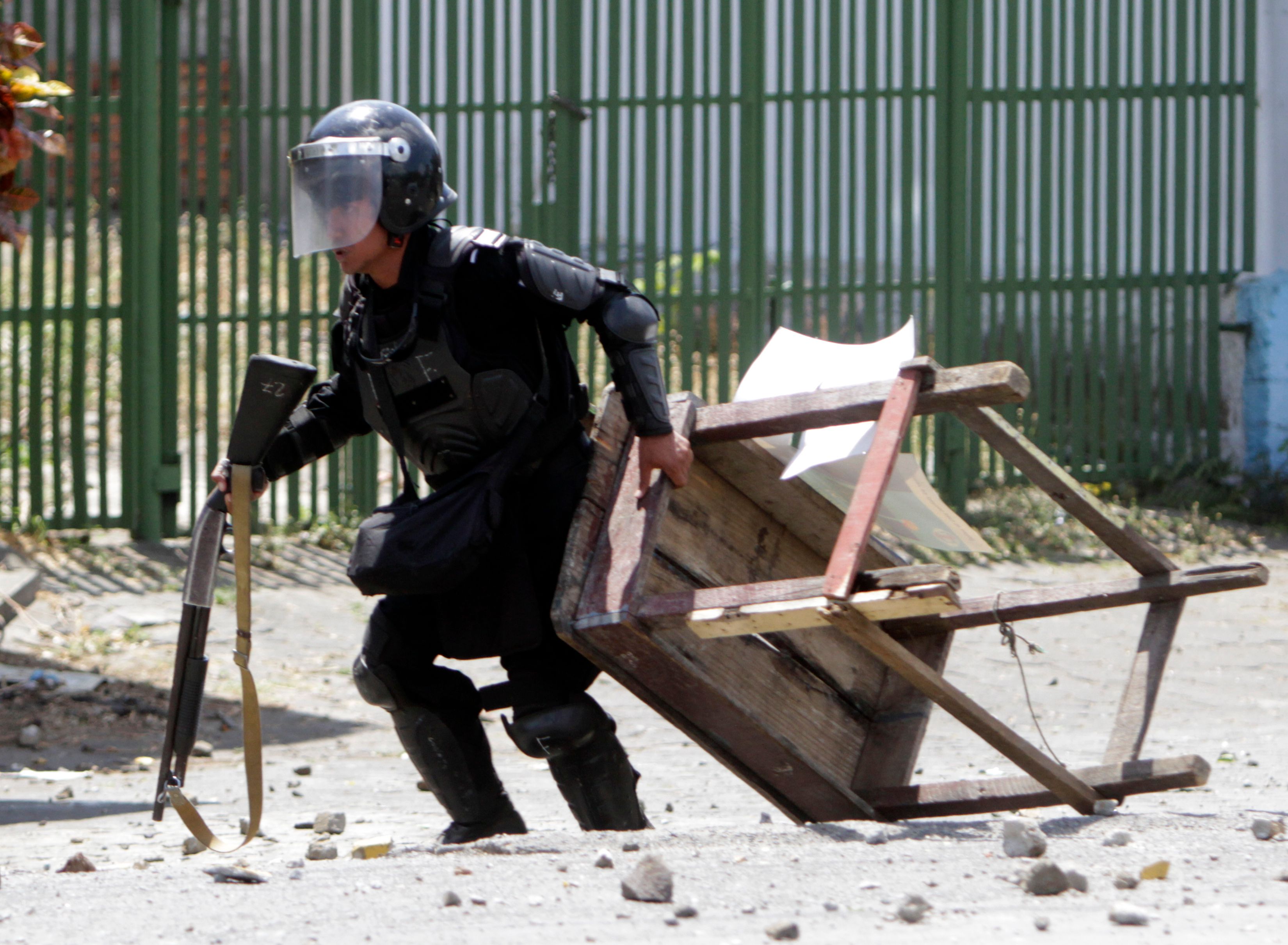 أحد عناصر الشرطة يحتمى من حجارة المتظاهرين