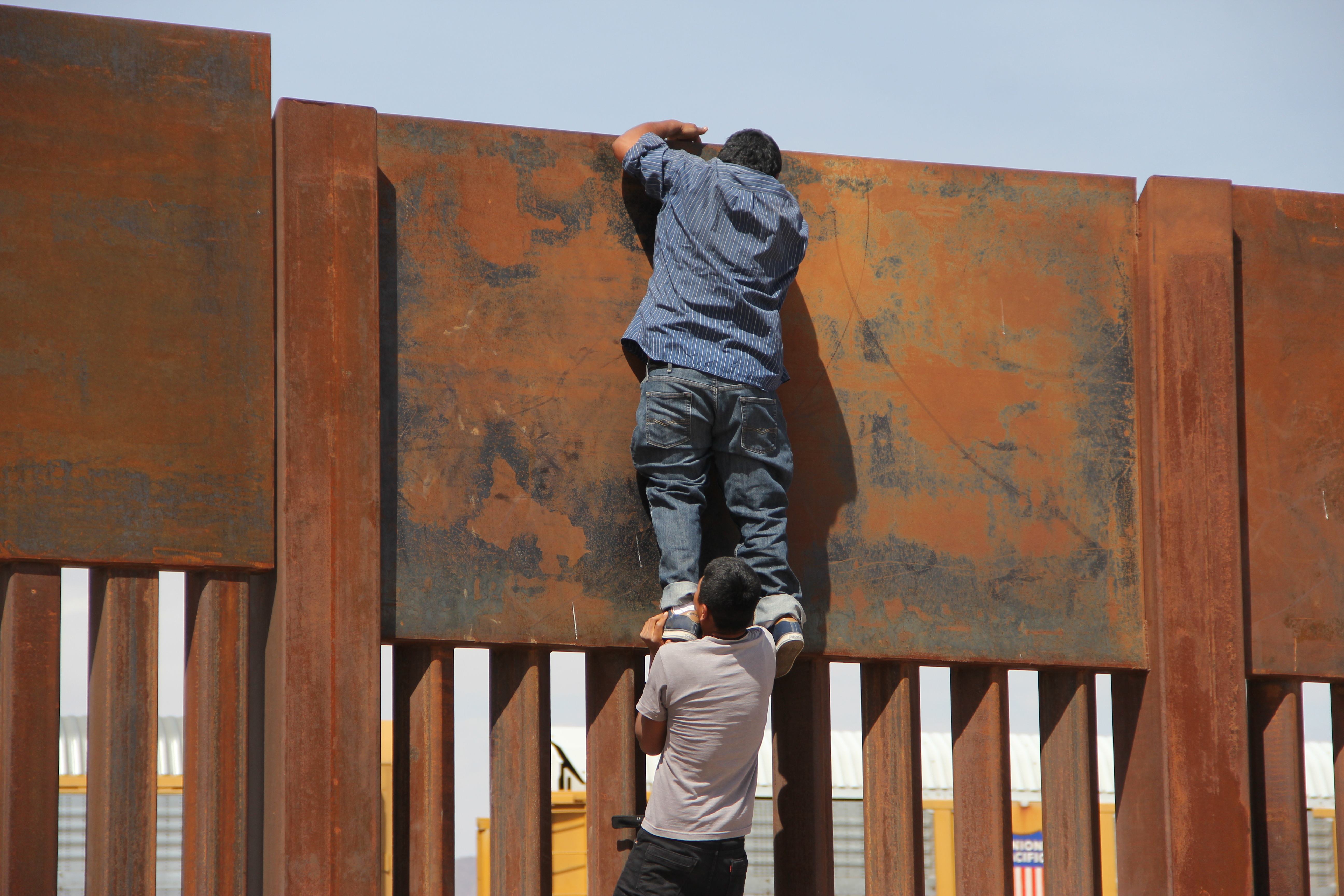 أحد المهاجرين يجتاز الجدار الحدودى بين الولايات المتحدة والمكسيك