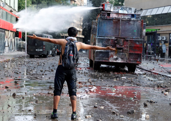 متظاهر يستعرض شجاعته أمام رشاشات المياه