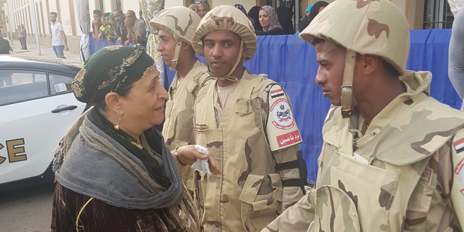 سيدة تقبل رؤوس جنود القوات المسلحة بلجنة انتخابية بالدقى: "ربنا يحميكم لمصر"