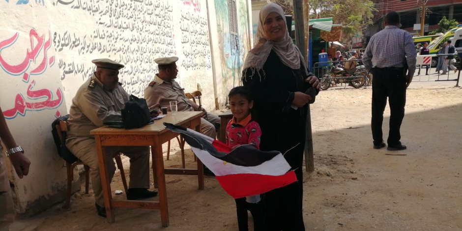 ربة منزل تصطحب طفلتها وبيدها علم مصر أثناء الاستفتاء: لتعليمها الانتماء 