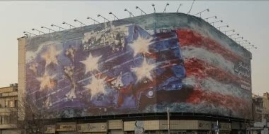 من يزرع الريح يحصد عاصفة.. إيران تحذر ترامب بعلم ملطخ بالدماء على لوحة إعلانية ضخمة في طهران