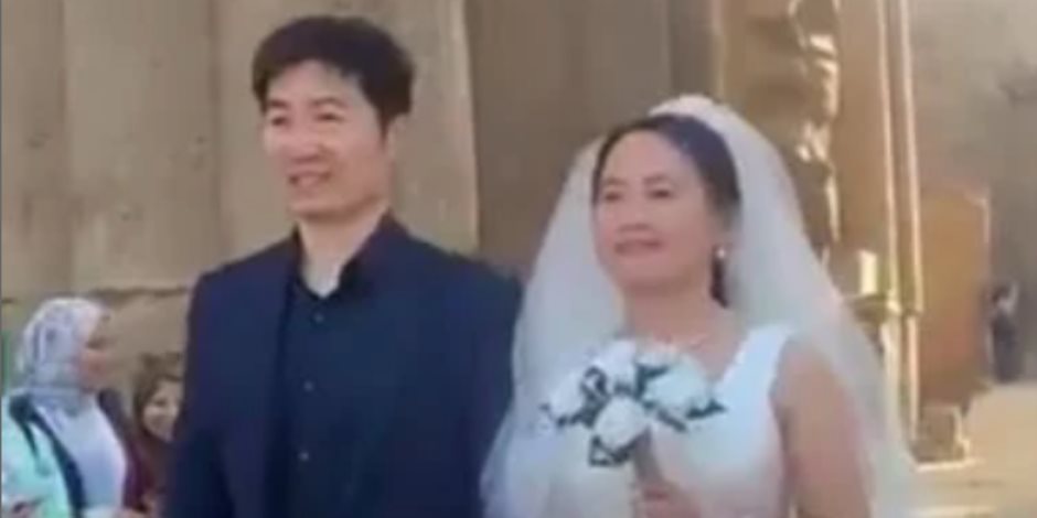 سائح صيني يحتفل مع زوجته بفستان وبدلة الزفاف في معبد الأقصر .. صور