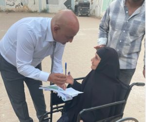 رئيس لجنة بالفيوم يتوجه إلى مسنة خارج اللجنة لمساعدتها على الإدلاء بصوتها