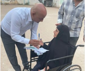 رئيس لجنة بالفيوم يتوجه إلى مسنة خارج اللجنة لمساعدتها على الإدلاء بصوتها