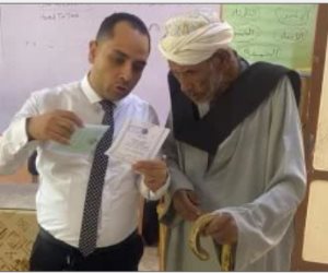قاضٍ يساعد مسنًا فى الإدلاء بصوته داخل لجنة كيما أسوان