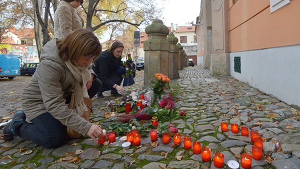 بالصورة.. سيدة فرنسية تضع علامة إستفهام بالشموع أمام السفارة الفرنسية فى براج